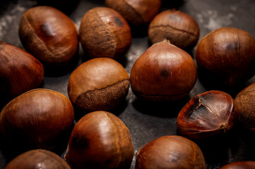 Roasted chestnuts on the background of a dark surface. The species of large plan, close