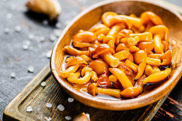 Marinated mushrooms on a wooden plate. 