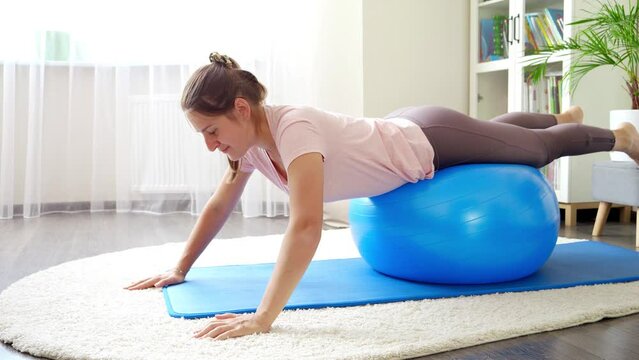 Beautiful young woman balancing and rocking on blue fitball. Concept of healthcare, sports and yoga at home