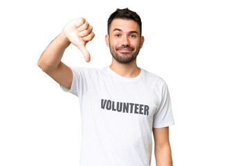 Naklejka premium Young volunteer caucasian man over isolated chroma key background showing thumb down with negative expression