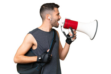 Young sport caucasian man with sport bag over over isolated chroma key background shouting through a megaphone