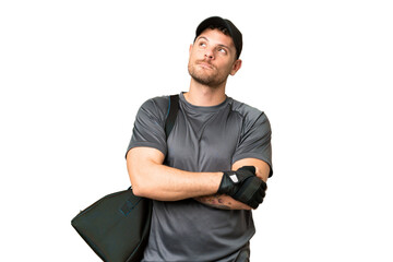 Young sport man with sport bag over isolated chroma key background looking up while smiling