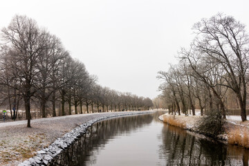 Fototapeta na wymiar Djurgårdskanalen (Djurgården canal) in Stockholm, Sweden in autumn with light snow cover and gray cloud sky as a river running into the distance