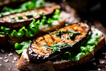 Delicious grilled eggplant sandwich. On a wooden background.