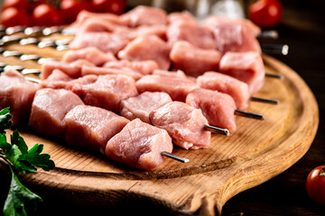 Pork kebab raw on skewers on a cutting board. 