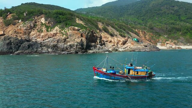 On sunny morning, fishing boat hurries to sea to catch seafood. Fishermen Nha Trang in Vietnam are sailing on a against the backdrop of a beautiful landscape and a wonderful mountains on a sunny day.