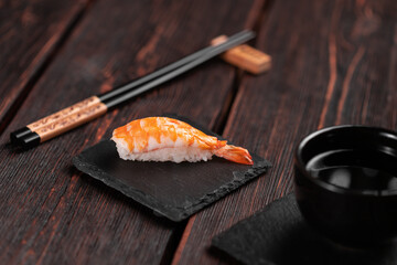 Japanese seafood sushi nigiri with shrimp on black and wooden background - asian cuisine concept