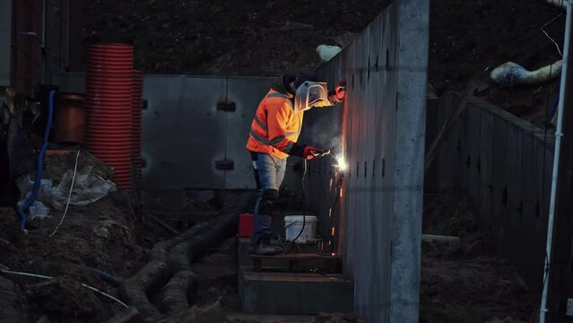 Skilled Construction Site Contractor Worker in Protective Wear Operating Electric Arc Welder