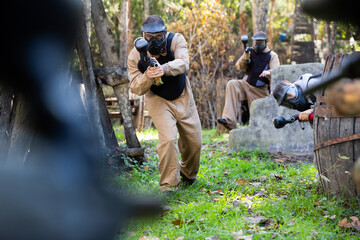 Group of people in full gear playing paintball on shooting range