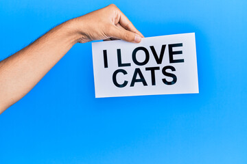 Hand of caucasian man holding paper with i love cats message over isolated blue background