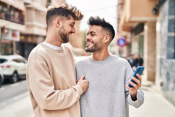 Young couple using smartphone hugging each other at street