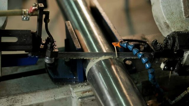 Cutting stainless steel pipes, the band saw for industrial cutting the metal stainless pipe and using the coolant heating. The industrial tool.