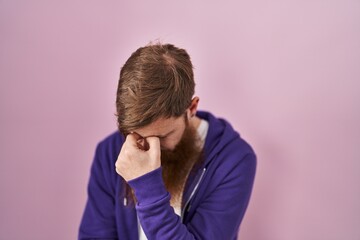 Caucasian man with long beard standing over pink background tired rubbing nose and eyes feeling fatigue and headache. stress and frustration concept.