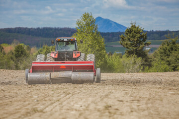Farmer is sowing seeds with agricultural seeder on a beautiful spring day.  Agricultural machinery equipment on farm. 