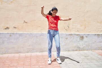 Obraz na płótnie Canvas Young hispanic girl smiling confident listening to music at street