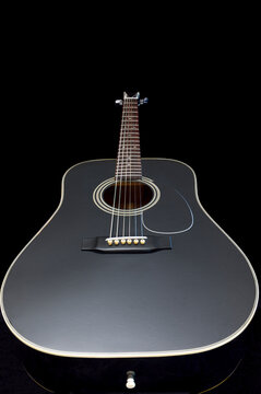 steel stringed acoustic guitar isolated against black