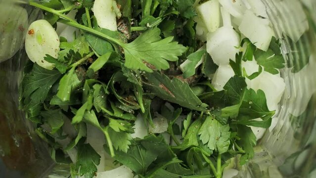 Bender grinds parsley celery onions and garlic with spices into green sauce