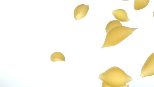 Dry pasta Conchiglie rigate flying diagonally on a white background