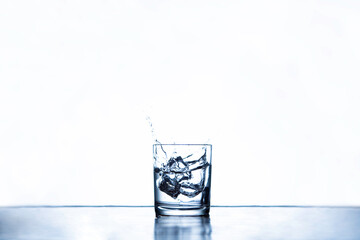 ice cubes splashing into glass water