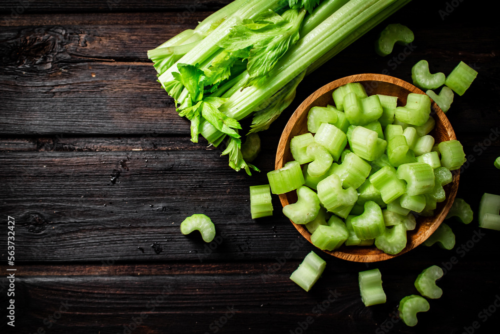 Poster Sliced fresh celery. On a dark wooden background.