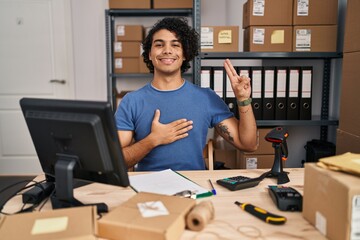 Hispanic man with curly hair working at small business ecommerce smiling swearing with hand on...