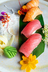 four nigiri sushi with salmon and tuna served on fresh green banana leaf on black background with japanese sign © leo