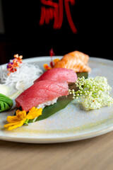 four nigiri sushi with salmon and tuna served on fresh green banana leaf on black background with japanese sign