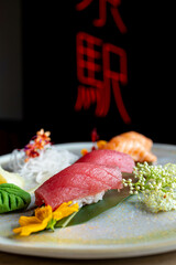 four nigiri sushi with salmon and tuna served on fresh green banana leaf on black background with japanese sign © leo