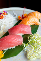 four nigiri sushi with salmon and tuna served on fresh green banana leaf on black background with japanese sign