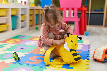 Adorable blonde girl preschool student opening backpack at kindergarten