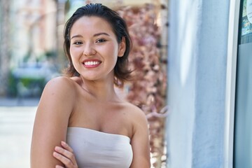 Young hispanic woman standing with arms crossed gesture at street