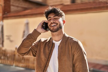 Young hispanic man smiling confident talking on the smartphone at street
