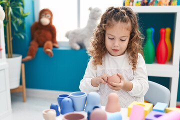 Adorable blonde toddler playing with toys standing at kindergarten