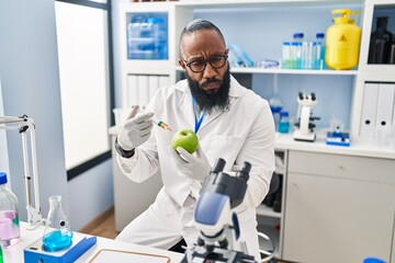 African american man working at scientist laboratory with apple depressed and worry for distress, crying angry and afraid. sad expression.