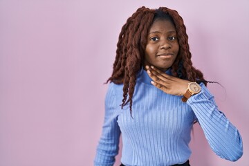African woman standing over pink background cutting throat with hand as knife, threaten aggression...