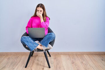 Young hispanic girl working using computer laptop tired rubbing nose and eyes feeling fatigue and...