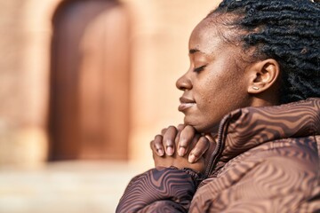 African american woman praying with closed eyes at street