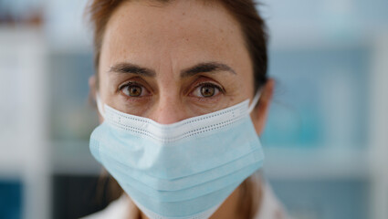Middle age hispanic woman wearing scientist uniform and medical mask at laboratory