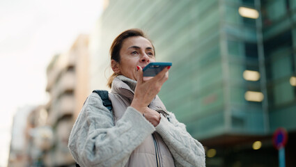 Middle age hispanic woman smiling confident talking on the smartphone at street