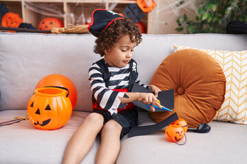 Adorable hispanic boy having halloween party drawing on balloon at home