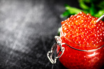 Red caviar in a glass jar with parsley. 