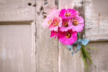 Fototapeta na wymiar Bouquet of Pink Zinnias Through the Doorknob of Old Wooden Doors