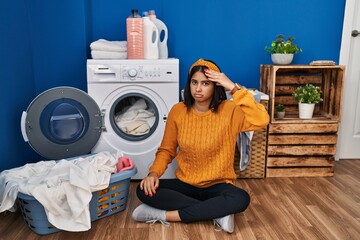 Young hispanic woman doing laundry worried and stressed about a problem with hand on forehead, nervous and anxious for crisis