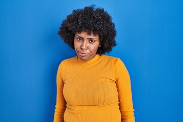 Fototapeta na wymiar Black woman with curly hair standing over blue background depressed and worry for distress, crying angry and afraid. sad expression.