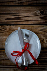 Knife with a fork with a red ribbon on a plate.