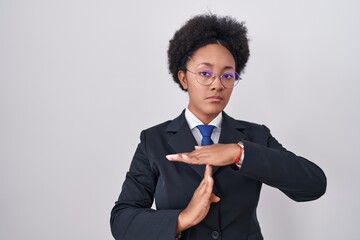 Beautiful african woman with curly hair wearing business jacket and glasses doing time out gesture...
