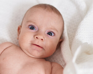 Adorable caucasian baby lying on bed with relaxed expression at bedroom