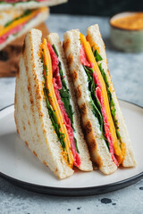 Two homemade sandwiches with sausage, cheese and arugula on a light concrete background