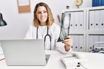 Young hispanic woman wearing doctor stethoscope holding xray at clinic