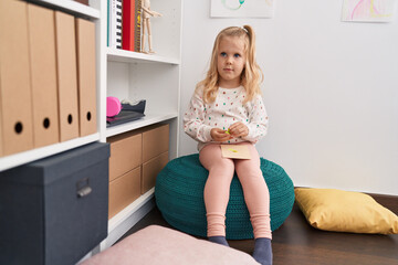 Adorable blonde girl holding paper target sitting at library school